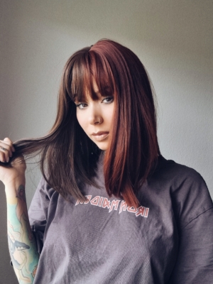 Ornate takes two barely-there shades with the split colouring technique. Straight down the middle so each colour of muted auburn and dark brown, falls to each side of the parting. A one length long bob styled straight, that a gentle curl under. With a sleek blunt fringe. 