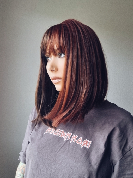 Ornate takes two barely-there shades with the split colouring technique. Straight down the middle so each colour of muted auburn and dark brown, falls to each side of the parting. A one length long bob styled straight, that a gentle curl under. With a sleek blunt fringe. 