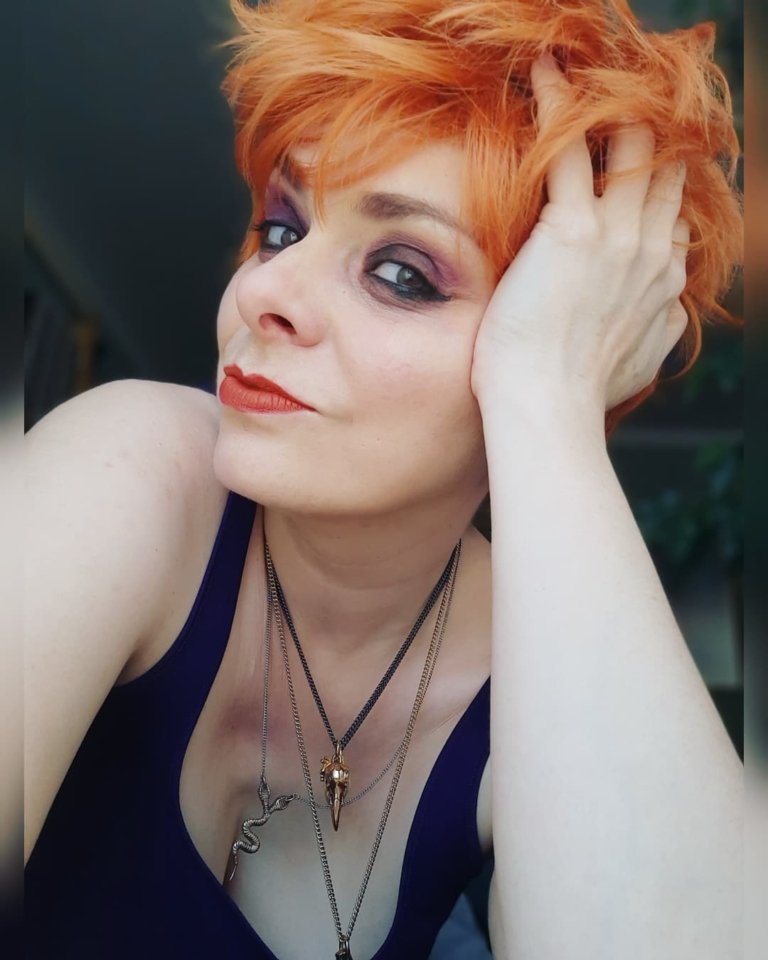 A cute pixie cut in a clementine orange colour. Sleek short layers are blow dried with a large barrel brush. Wear it forward or swept to the side away from the face.