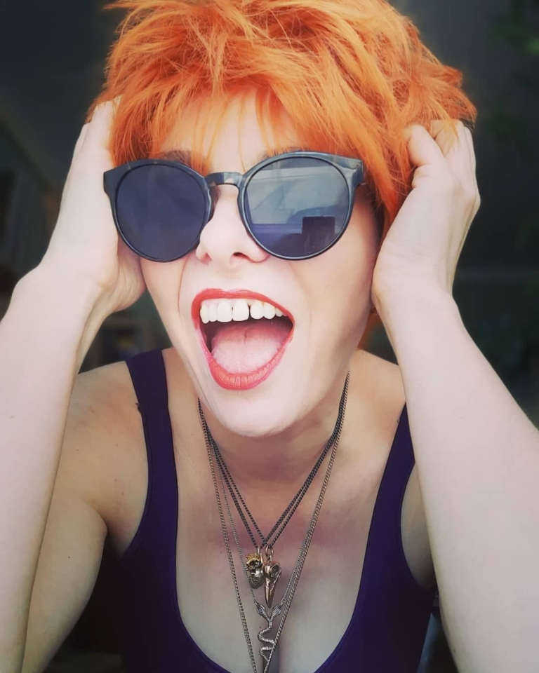 A cute pixie cut in a clementine orange colour. Sleek short layers are blow dried with a large barrel brush. Wear it forward or swept to the side away from the face.
