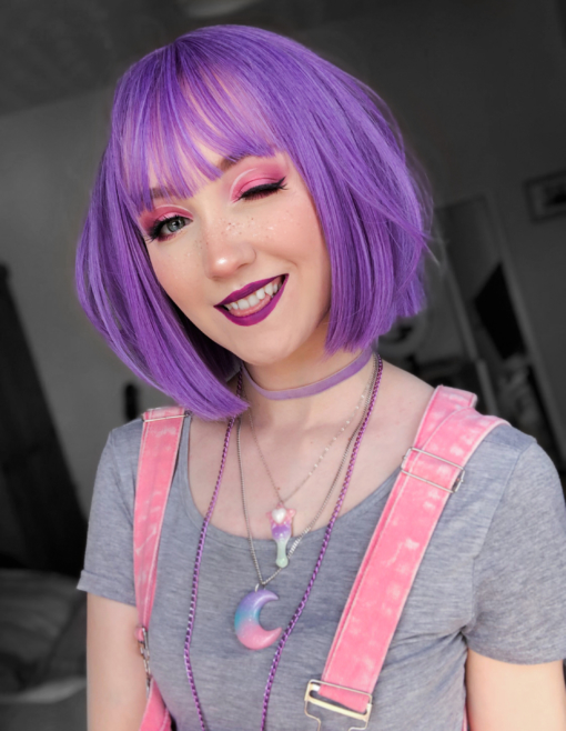 Bright light purple straight bob wig with bangs. Our pastel A-line bob Touka is a mixture of dark and light lilacs, creating this orchard colour. A simple jaw-skimming cut that ensures you get heads turning.