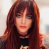 Muted red long straight wig with bangs. Blood moon has a mix of nocturnal colours. Black roots that melt into a deep muted cherry red ombre that's carried through the fringe. The sleek and thick texture falls to the waist. 