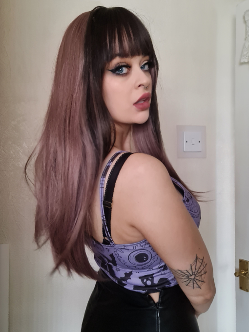 Lilac long straight wig with bangs. Bang on trend, Ballerina is a luscious mauve colour with a bold slice of a dark brown colour that falls on each side and carried through the fringe to frame the face. Long and sleek with layers for movement.