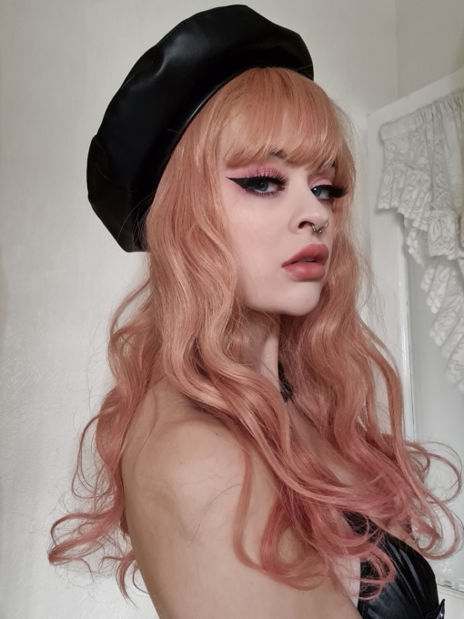 Strawberry blonde wavy long wig with bangs. A gorgeous faded peach colour from the roots, with rosy pink dipped dye ends. Styled in loose tumbling curls, finished with a fringe that is light and airy.
