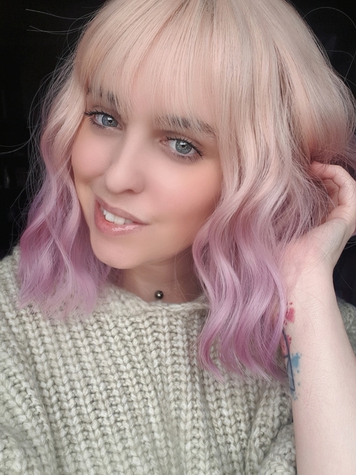 Blonde and pink wavy bob wig with bangs. Buttercup has a natural twist of vanilla roots that carry a washed-out pastel pink. Styled in loose waves to give texture and body, with a wispy fringe to frame the face.