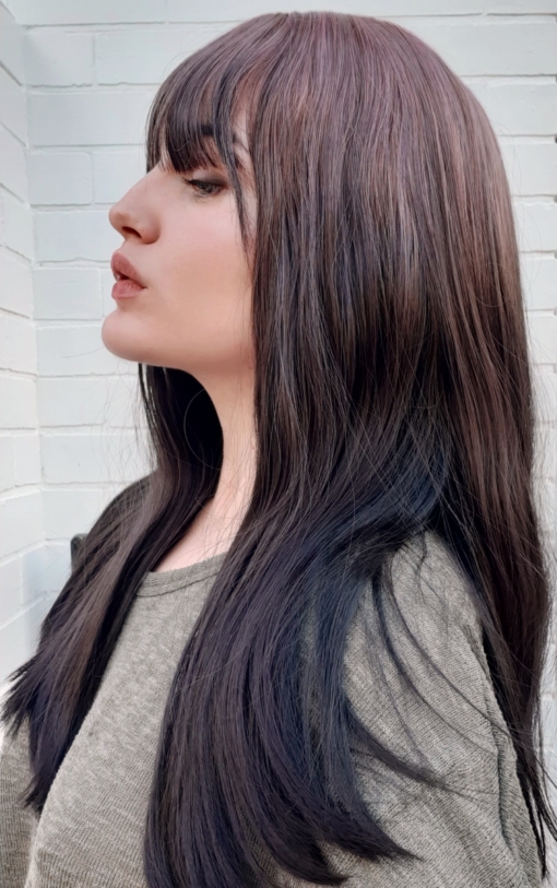 Brown and lilac reverse ombre straight wig with bangs. We can't get enough of this eye-catching style. Nightshade is heavily influenced by the reverse ombre. Only the deep lilac tone is focused on the roots, blending into a very dark (almost black) brown colour. Poker straight with a light fringe.