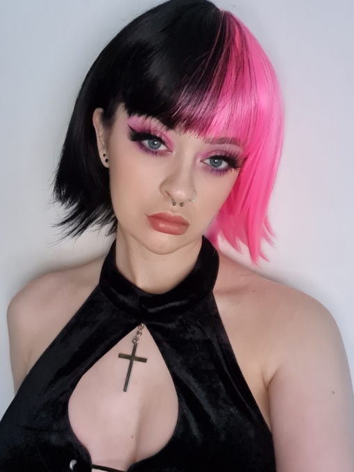 Pink and black split section straight bob wig with bangs. Galah takes on the dramatic colour divide. A vivid deep pink section from the centre parting, through the fringe, across to the ear, leaving the rest of the head a black colour. A straight blunt cut with a wispy fringe.