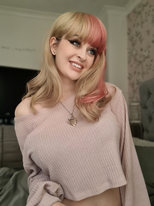Blonde and pink long wavy wig with bangs. Zarita is a sandy blonde colour with a chunky block of pink flamingo hue running down the one side of the style, that runs into half of the fringe. This style doesn't disappoint. Wear it as a pop of colour, or mess it up. Good for those who are new to wigs, as it's easy to wear and maintain.