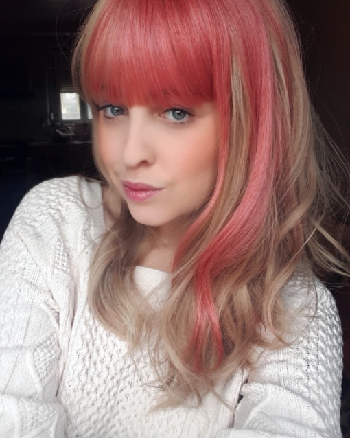 Zarita - Lush Wigs UK Blonde and pink long wavy wig with bangs. Zarita is a sandy blonde colour with a chunky block of pink flamingo hue running down the one side of the style, that runs into half of the fringe. This style doesn't disappoint. Wear it as a pop of colour, or mess it up. Good for those who are new to wigs, as it's easy to wear and maintain.