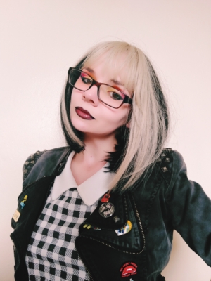 This straight bob that curls under at the ends. Comes with a bold money-piece face framing highlight of blonde. The rest of the hair is a dark brown colour. The sleek blunt fringe carries the blonde colour.