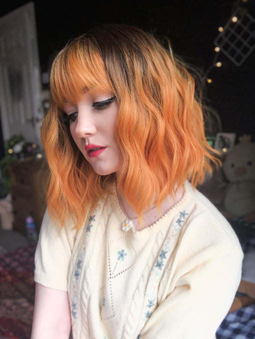Golden sunset tones of amber with brown shadowed roots give a natural feel to the look. Textured tousled waves are lightweight and manageable. This bob falls just above the shoulders with a blunt fringe to finish the look.