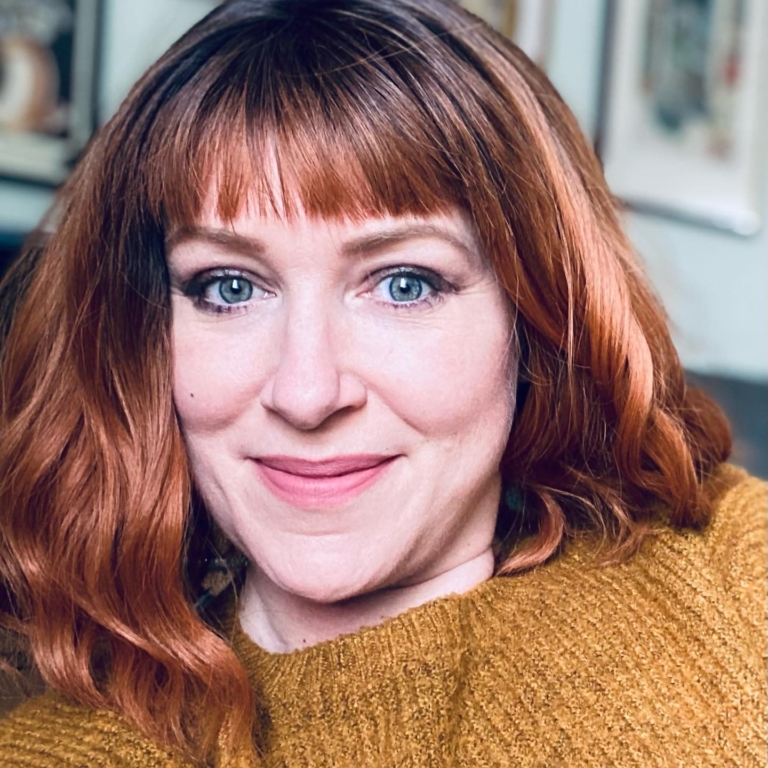 Embers - Lush Wigs UK A dark apricot wig with brown shadowed roots. Styled into a bob with loose waves and a sleek blunt fringe.