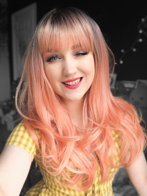 Brown and peach long straight wig with bangs. Be the belle of the ball in Flamingo! With its dark brown overgrown roots. A fresh peach sleek blow out style with a light airy fringe to frame the face.