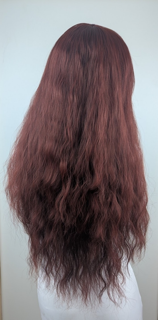 Babooshka is a rich auburn hue with a dash of paprika from roots to tips. Think of braids let loose to create mermaid waves that falls just to the waist. The long sleek fringe allows the freedom to choose between straight across bangs or more of a side fringe.