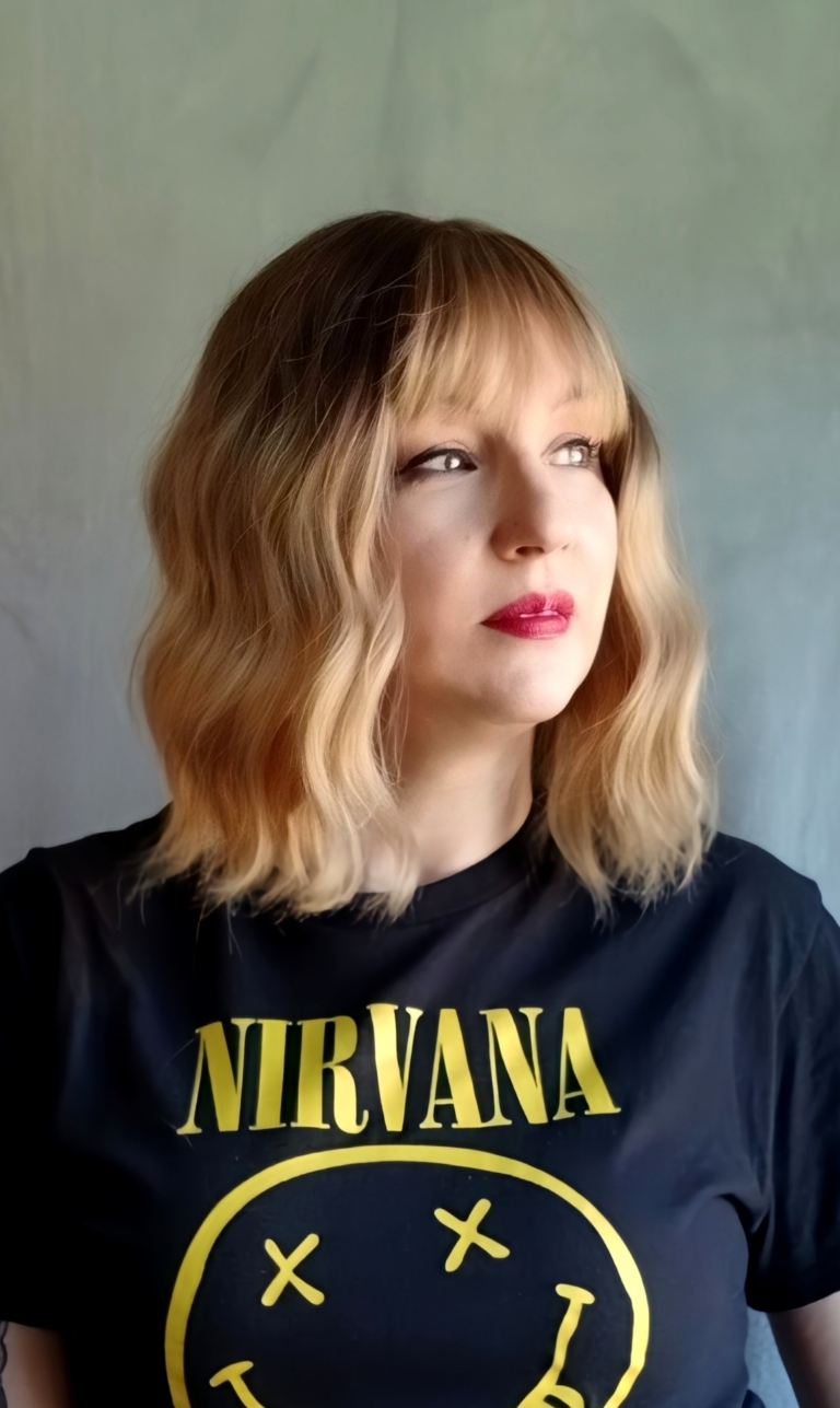 This bob is coloured in a honey blonde tone with brown shadowed roots. That gives a natural feel to the look. A loose wave and a sleek fringe finishes the look.