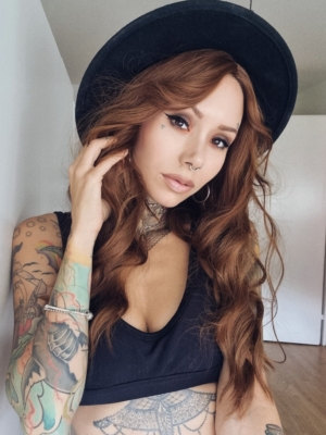 A natural golden brown hue from roots to tips. Long lengths are styled into relaxed barrel curls. With a sleek curtain bangs that fall to the jawline.