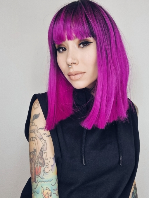 This poker straight lob (long bob) packs a punch with its magenta purple colour. A vivid shade with dark brown shadowed roots and a full fringe that carries the colour. The lengths are thick and one length, that fall just past the shoulders.