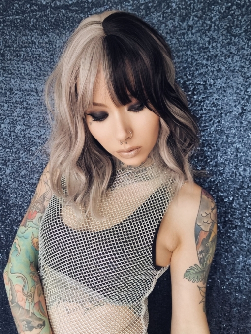 Platinum blonde with a mix of grey. A slice of jet black for added definition takes this style to the next level. Black tones come from the nape of the neck. Giving a peek-a-boo effect. Loose waves fall just past the shoulders, a wispy fringe frames the face.