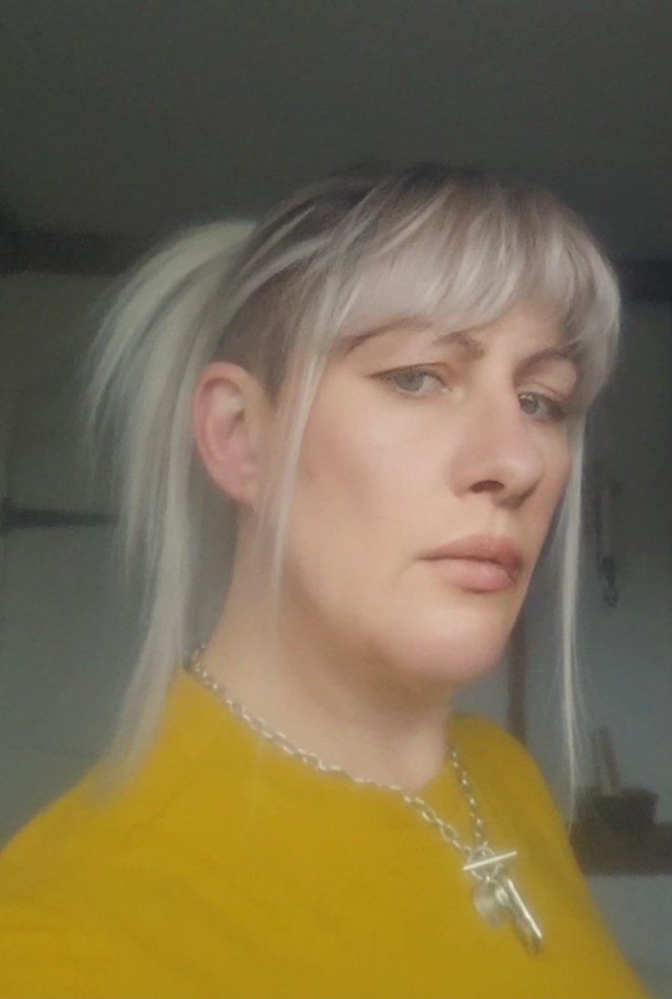 Dark brown shadowed roots blend into a sterling blonde colour. Cut into long straight layers to add fullness and movement. A blunt sleek fringe finishes the look.