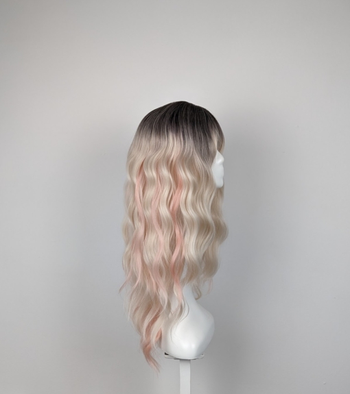 Dark brown shadowed roots melt into a light blonde with subtle pastel peach pink strands for that peek-a-boo effect. Long loose waves with long invisible layers adds movement and body. A light fringe frames the face.