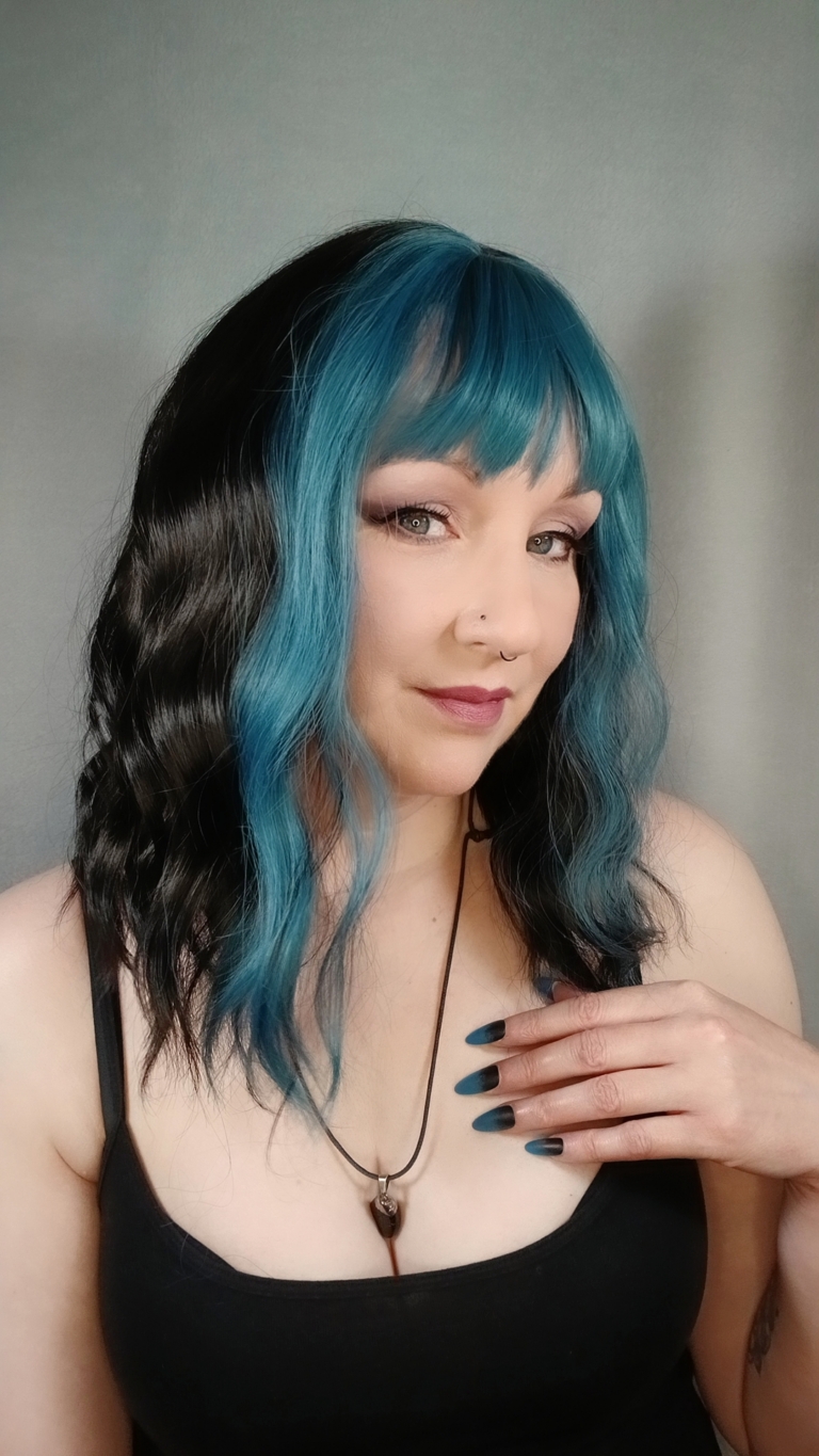 This wavy dark brown bob comes to life with a face framing peek-a-boo slice of denim blue colour. Thats carried into the blunt sleek fringe.