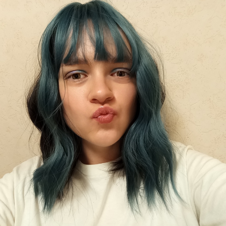 This wavy dark brown bob comes to life with a face framing peek-a-boo slice of denim blue colour. Thats carried into the blunt sleek fringe.