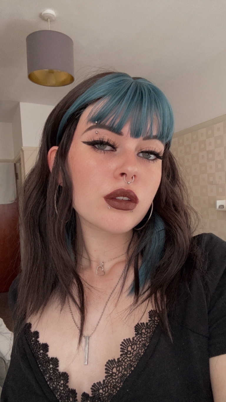 This wavy dark brown bob comes to life with a face framing peek-a-boo slice of denim blue colour. Thats carried into the blunt sleek fringe.