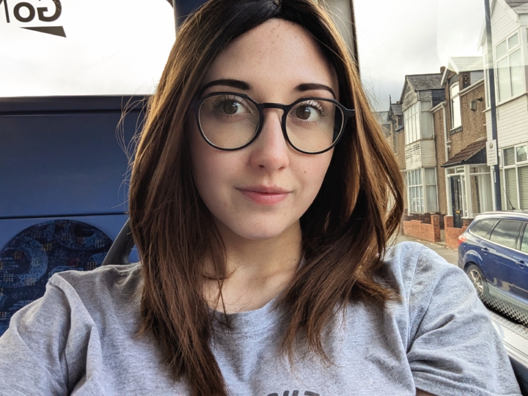 Natural dark brown shadowed roots blend into a warm light brown tone. This fringeless long bob (lob) with two layers each side of the face. Is sleek with a whisper of a wave that curls under.