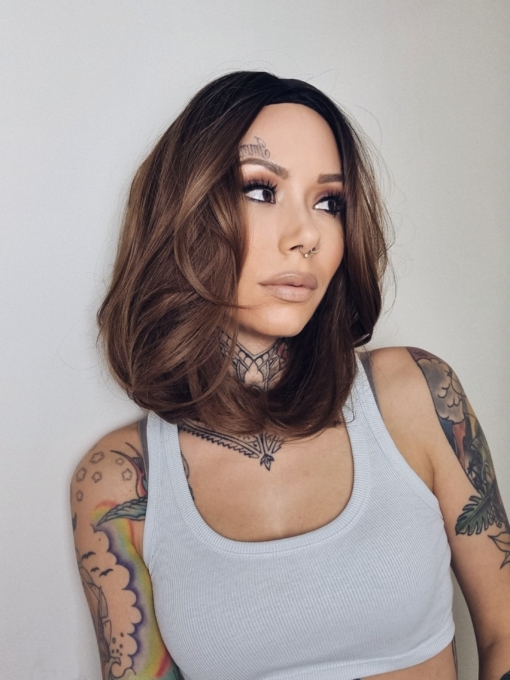 Natural dark brown shadowed roots blend into a warm light brown tone. This fringeless long bob (lob) with two face framing layers each side of the face. Is sleek with a whisper of a wave that curls under.