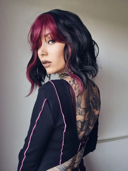 This wavy bob comes to life with a face framing slice of bright purple colour. Thats carried into the fringe and adds a peek-a-boo at the sides. A soft black colour from roots to tips.