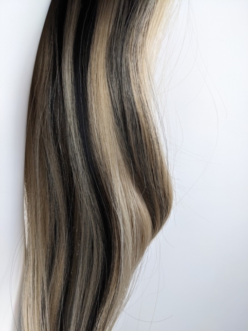 Sandy blonde with brown streaks coming from the nape of the neck, for a peek-a-boo effect with a full fringe. A Blow out style falls to the waist
