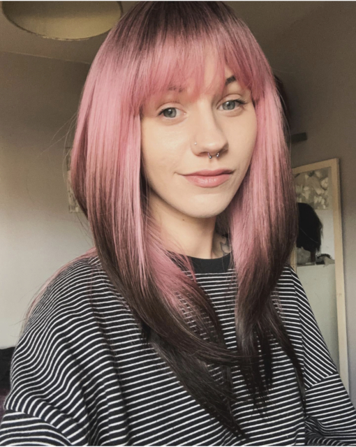 This natural twist soft black wig with a bright pink pop of colour. Soft black roots blend into this dusky pink hue with black tips. A sleek long style with long layers at the back, face framing layers at the front make this style easy to maintain. With a full fringe to peep from under.