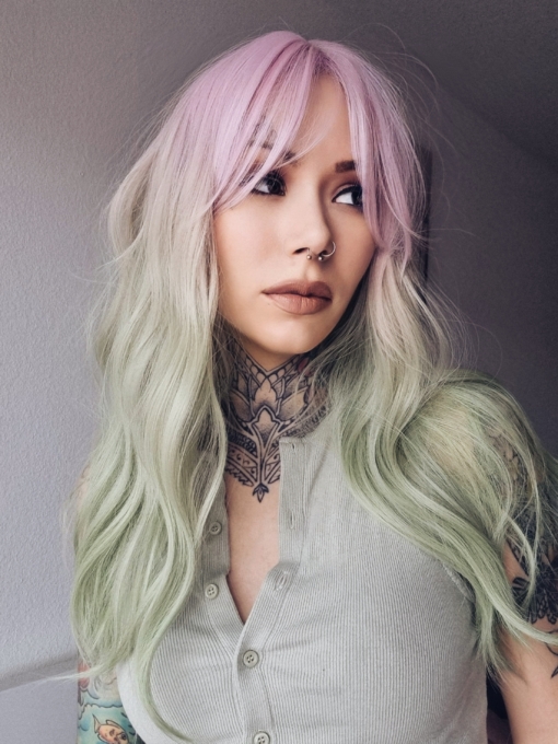 A mix of pastel pink from the roots that melt into a pastel green ombre. The style is sleek from the roots with a gentle wave for this one length long style. A light pink fringe frames the face.