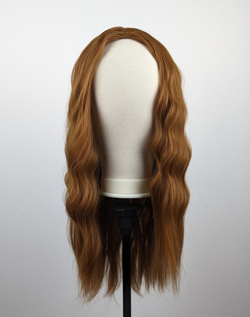 A mix of light browns and ginger produce this natural looking wig. Sleek from the roots with a braided effect wave. Cut into long layers. The fringeless centre part is styled away from the face, with volume and lift from the roots.