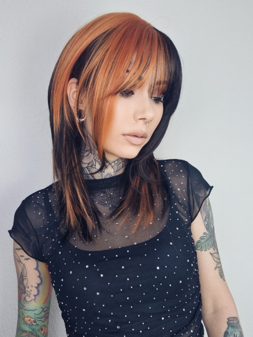 This vivid and bright wig has a natural twist of black and burnt orange. Blocks of colour set the look for this sleek long bob (lob) with a light airy fringe that carries the colour.
