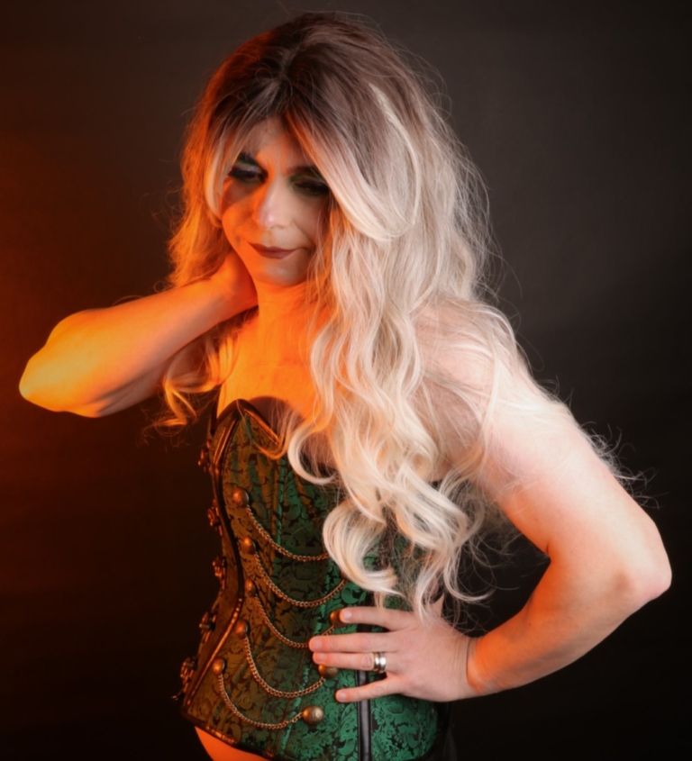 A mix of dark brown and blonde sleek roots that blend into a sandy blonde colour. It is styled in big loose curls. The sleek long fringe is versatile to be worn to suit your look.