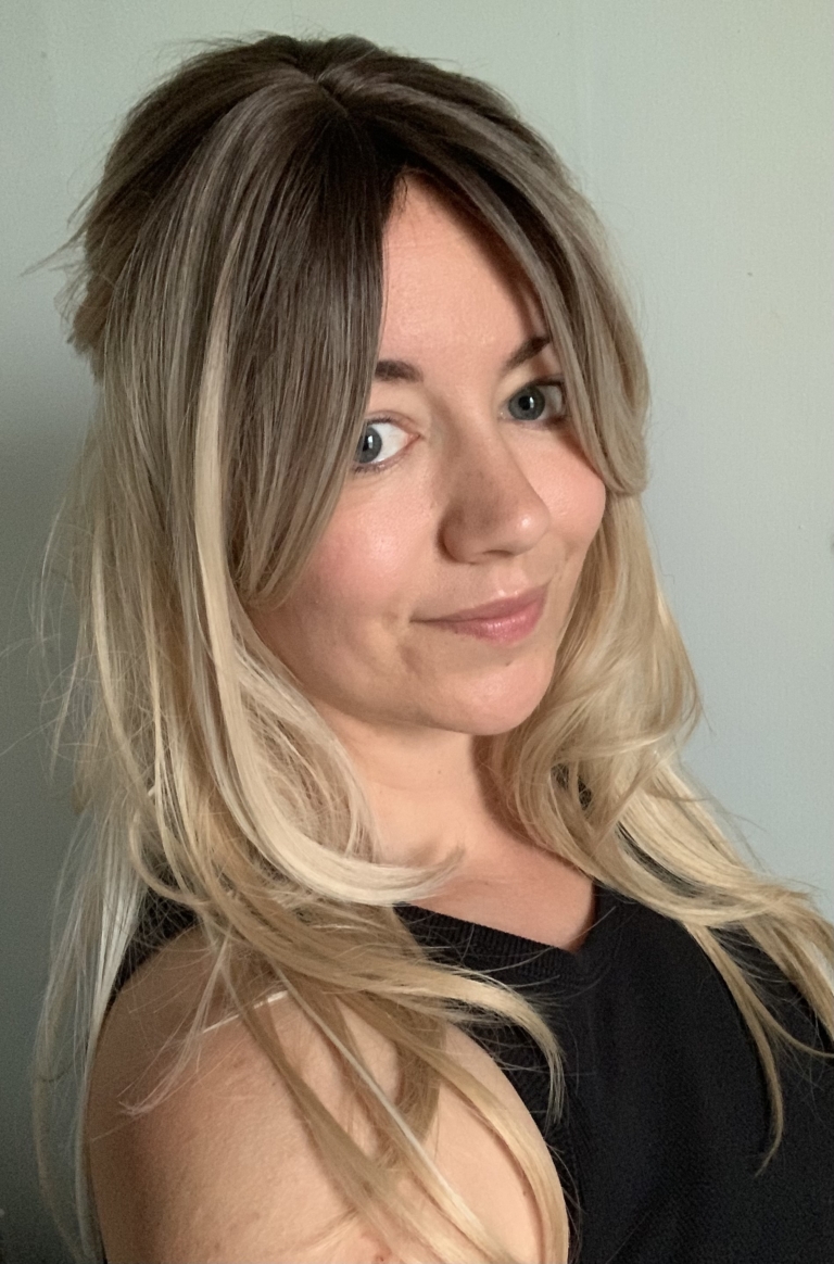 Ava - Lush Wigs UK A long and sleek wig with natural dark brown shadowed roots. They blend into a honey blond with sterling blonde highlights. Styled into sleek long layers and a long fringe that can swept to the side or parted into curtain bangs.