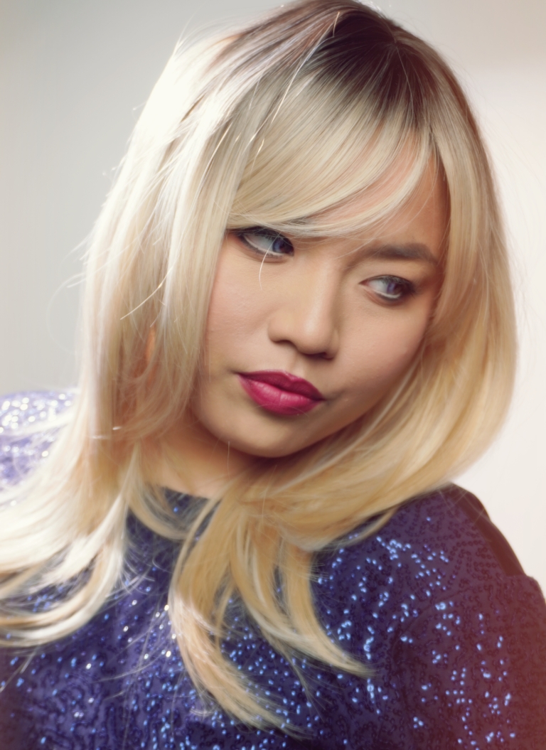 Ava - Lush Wigs UK A long and sleek wig with natural dark brown shadowed roots. They blend into a honey blond with sterling blonde highlights. Styled into sleek long layers and a long fringe that can swept to the side or parted into curtain bangs.