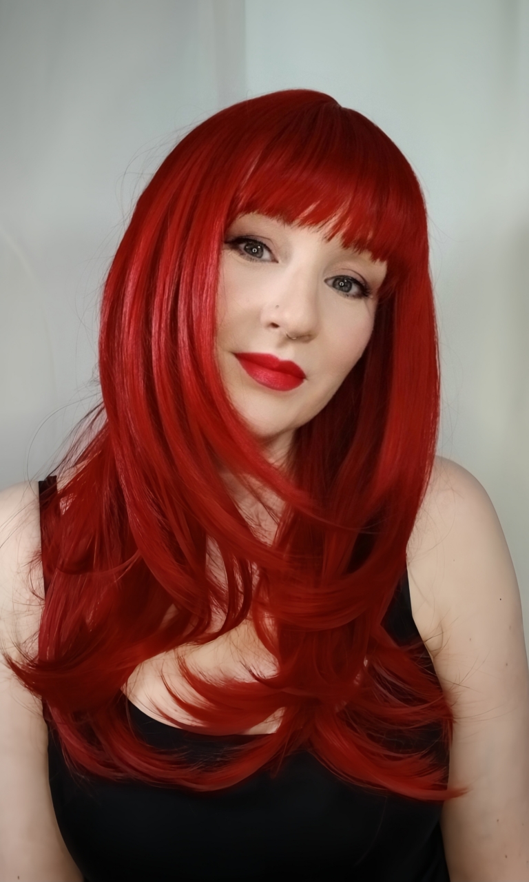 Smitten - Lush Wigs UK This sleek style comes in a vivid fire engine red colour from roots to tips. Cut into long layers that fall to the waist. Finished in a barrel brush blow out, with a sleek blunt fringe.
