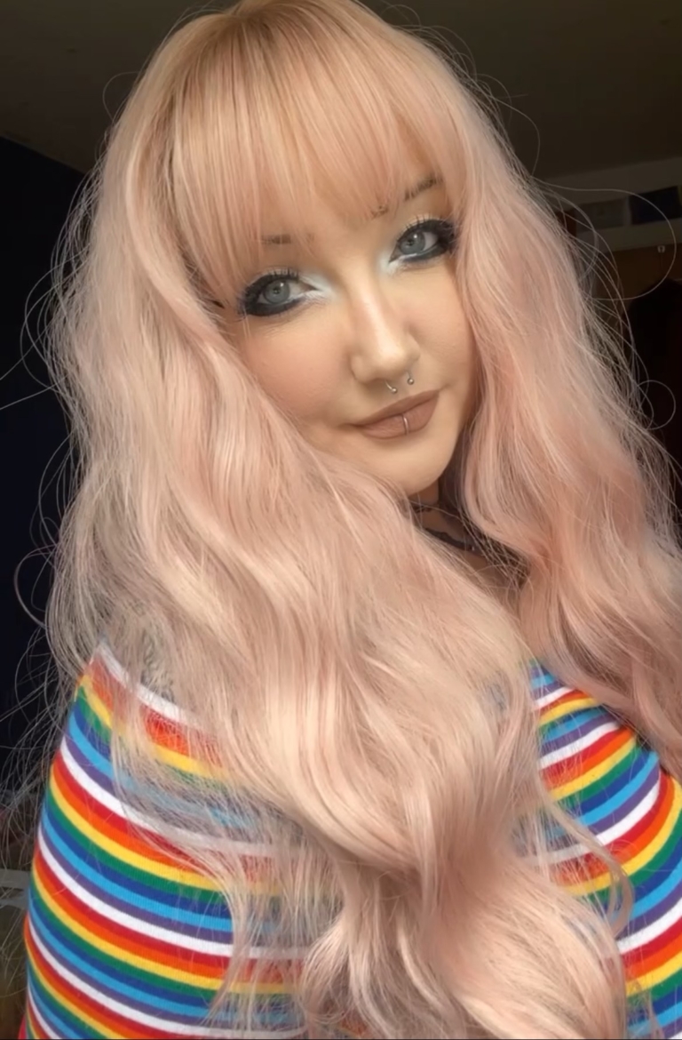 Long loose barrel curls set the look of this style. Light brown shadowed roots give a natural feel to this pastel creamy mix of blonde and pink. A light fringe carries the colour.