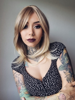 This long bob (lob) carries a sandy blonde colour blends into a light sun-kissed blonde for an ombre effect. It is cut into layers and a long fringe that can be parted into curtain bangs. Sleek with a gentle curl under at the ends.