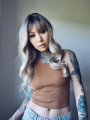 Icelyn - Lush Wigs UK A wig with brown shadowed roots that blend into a sandy blonde colour with sterling blond tips. The style is sleek and long with loose barrel curls from the mid-section. the fringe is blunt and sleek.