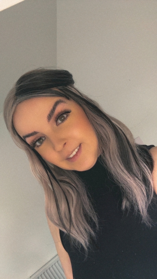 Eclipse - Lush Wigs UK Sterling blonde with a mix of grey. A slice of jet black for added definition takes this style to the next level. Black tones come from the nape of the neck. Giving a peek-a-boo effect. Loose waves fall just past the shoulders, a blunt sleek fringe carries the split colour.