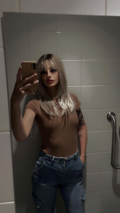 A wig with a mix of dark brown shadow roots that blend into a icy platinum blonde colour. The style is long and sleek with layers. Finished with a blow out turn at the ends.
A long sleek fringe can be parted into curtain bangs or swept to the side.