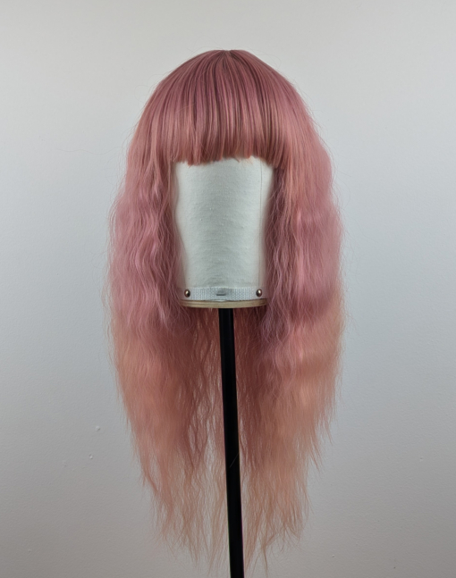 Outlet #140 - Lush Wigs UK This wig is so fluffy. A soft crimped mermaid waves style in a blend of coral pink that fades into a warm-toned peach. The sleek long fringe is versatile to be worn to suit your look.