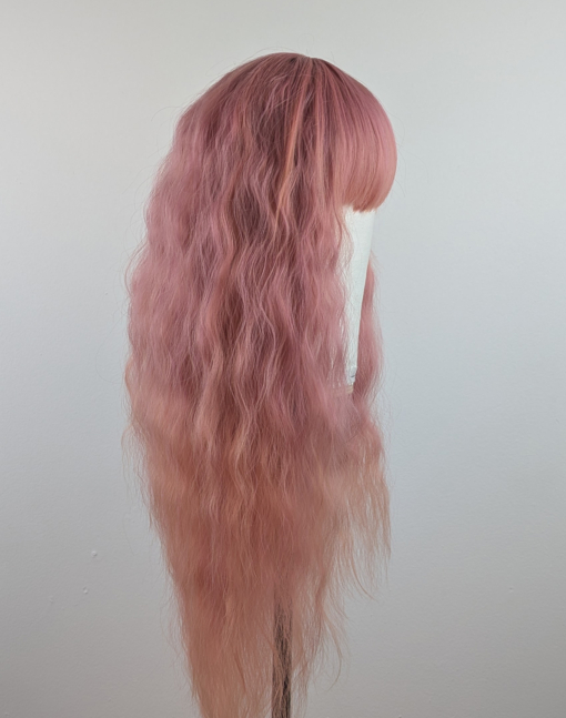 Outlet #140 - Lush Wigs UK This wig is so fluffy. A soft crimped mermaid waves style in a blend of coral pink that fades into a warm-toned peach. The sleek long fringe is versatile to be worn to suit your look.
