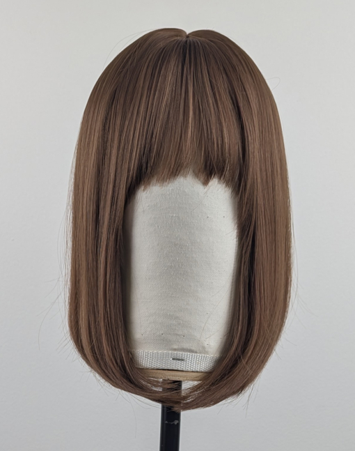 This natural brown colour wig is simple and easy to wear. Its rich brown shades come to life with golden-copper undertones. A sleek long bob (lob) that curls just under at the ends. With a light sleek fringe.