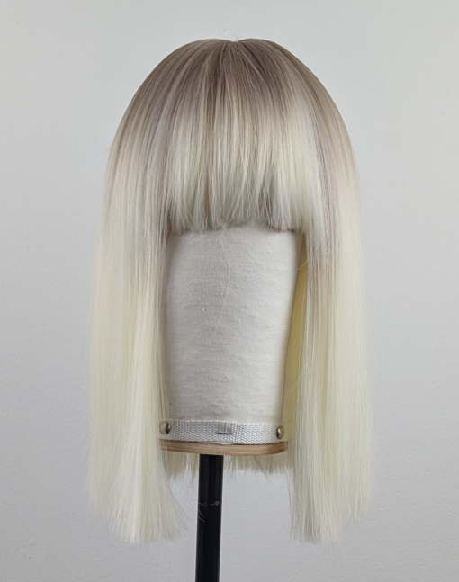 Outlet #147 - Lush Wigs UK A platinum blonde colour with a muted lemon undertone, producing a bleach blonde effect. A sprinkle of sandy blonde roots, creating a natural feel. Poker straight, long one length bob (lob) with a sleek full blunt fringe.