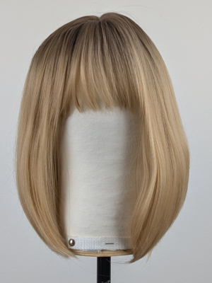This sandy natural blonde wig is simple and chic. Brown shadowed roots melt into a blonde hue with sun-kissed tips that create the perfect shades for a natural look. A straight one-length bob that curls under at the ends.