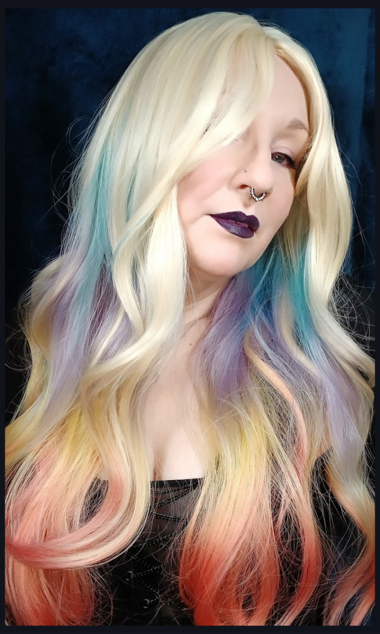 This multi-colour wig is a mixture of purple, blues, limes, greens and peach. From the nape of the neck giving a peek-a-boo effect. A natural blonde colour from the roots, thats carried into the sleek blunt fringe. Long and curly with invisible layers for bounce and volume.